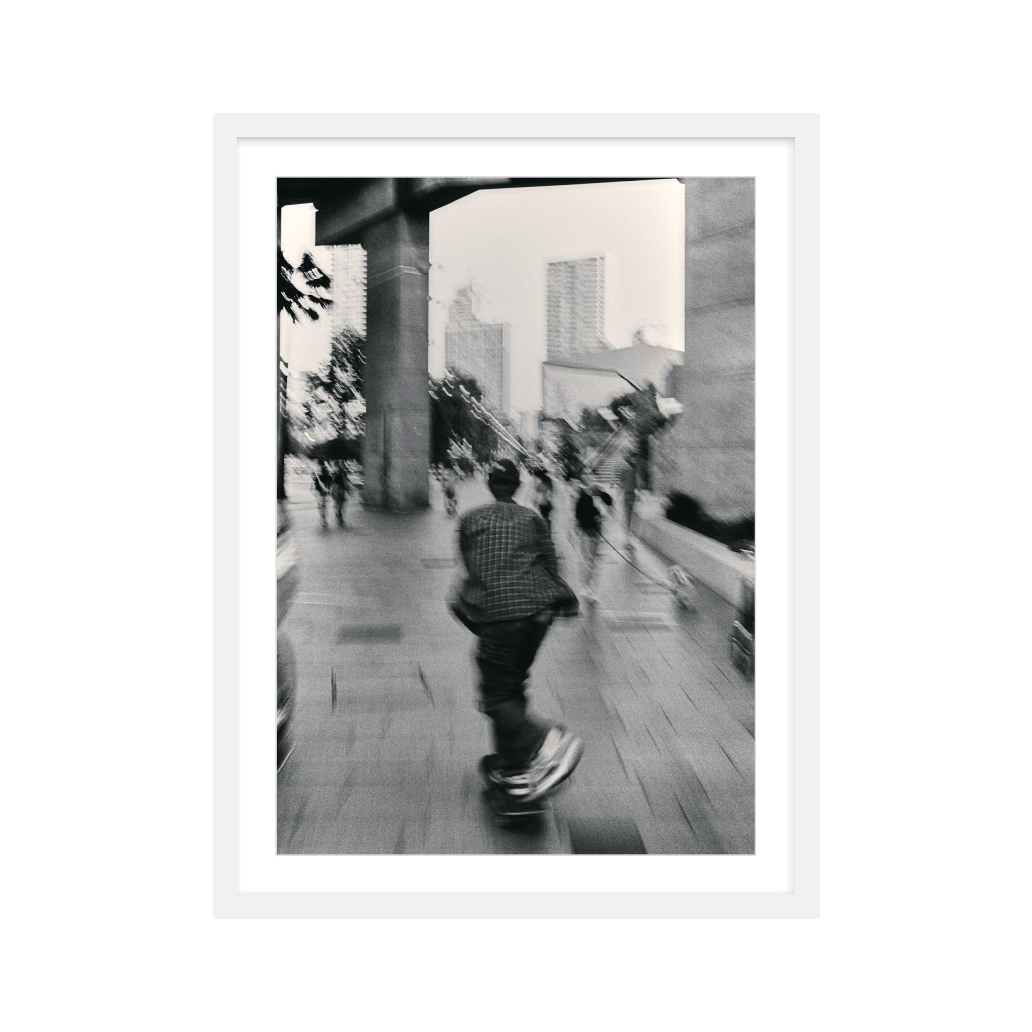 Black and white framed photo of a man on a skateboard performing a trick.