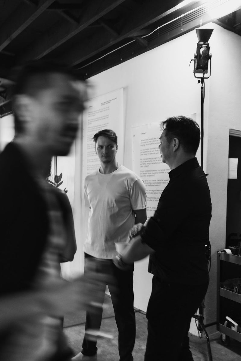 Three men in a room from a community meeting for journal brand memoirs by him