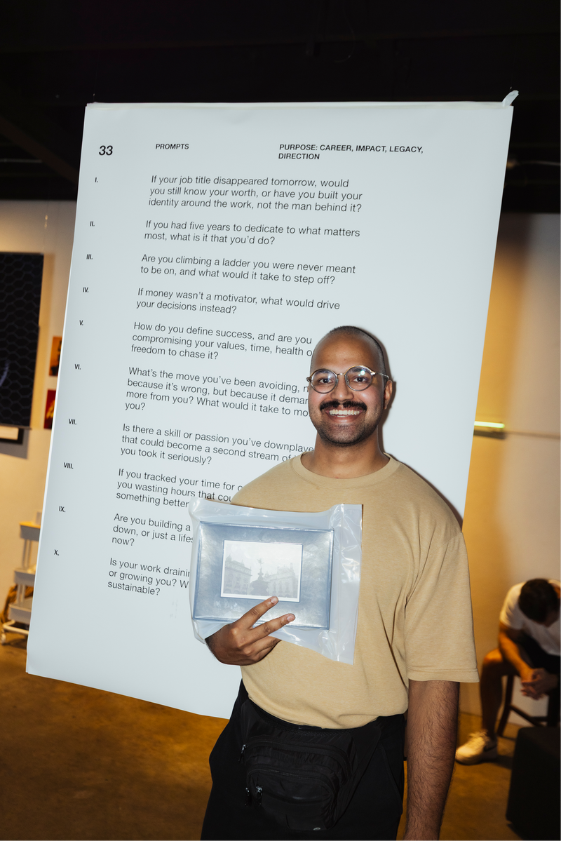 Man holding a framed picture in front of a large sheet of paper with prompts from memoirs by him journal event