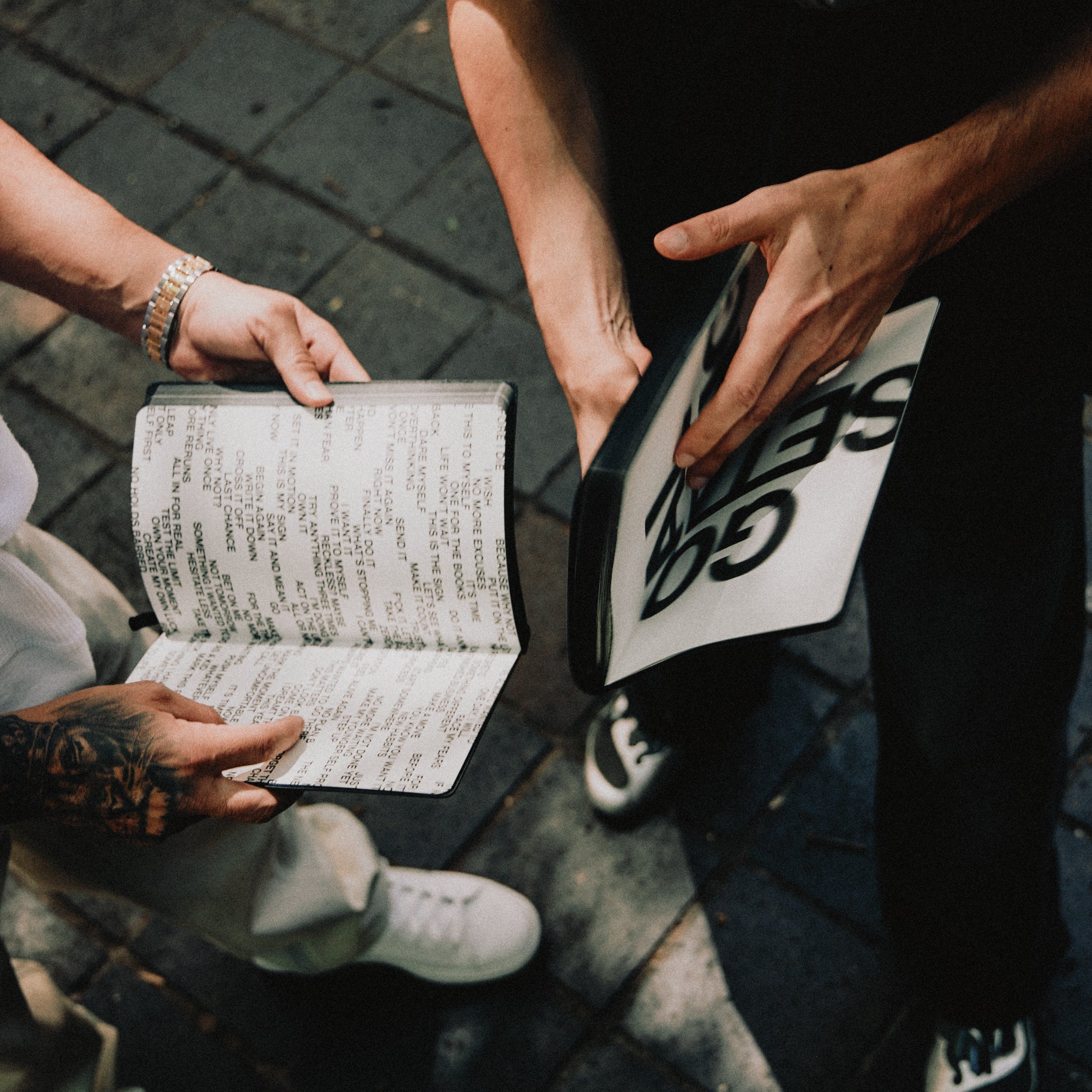 Two people holding open journals on a textured surface