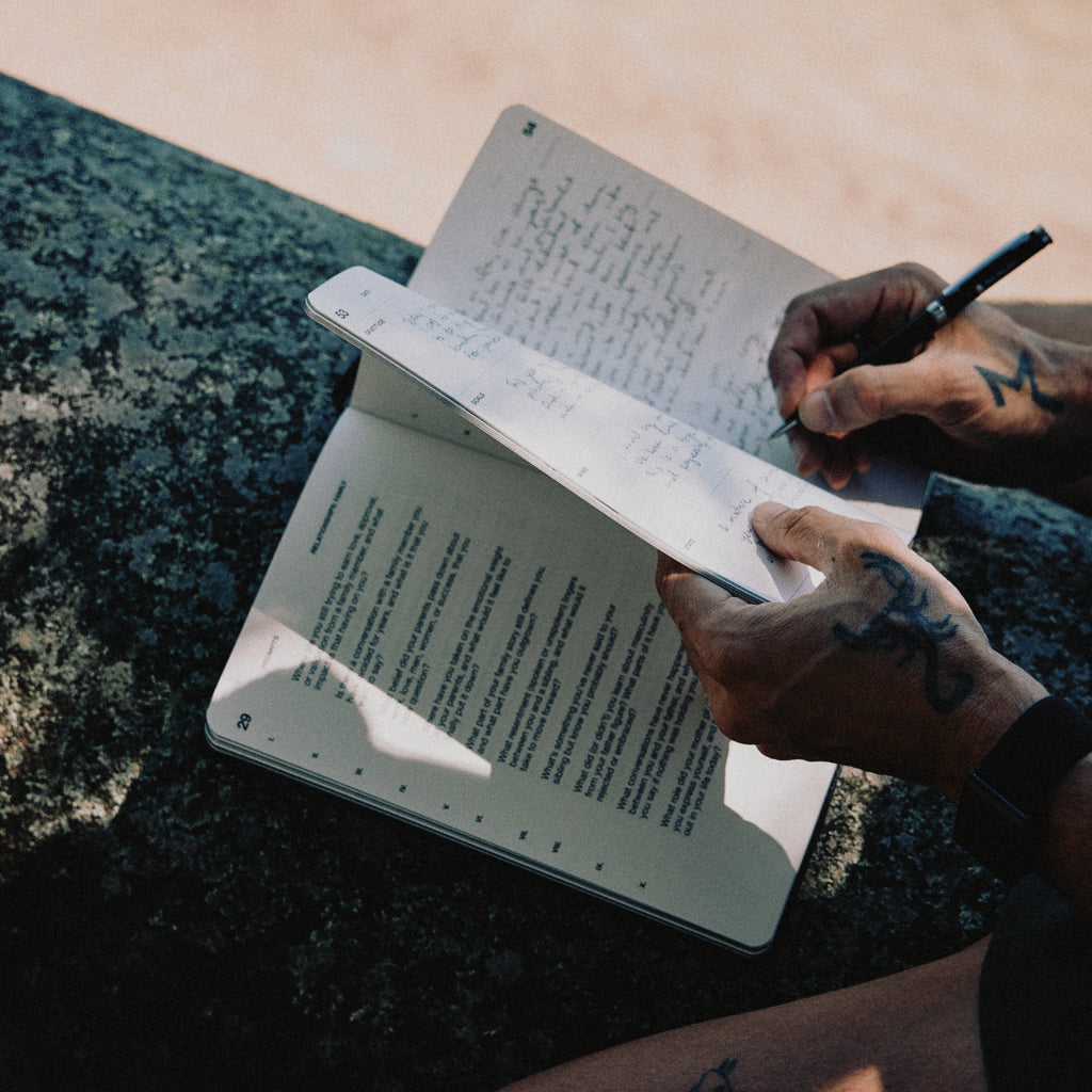 Person holding and writing in a journal with a pen.